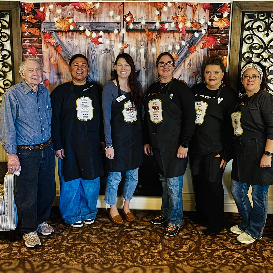 Team members smiling in front of an Autumn themed backdrop.