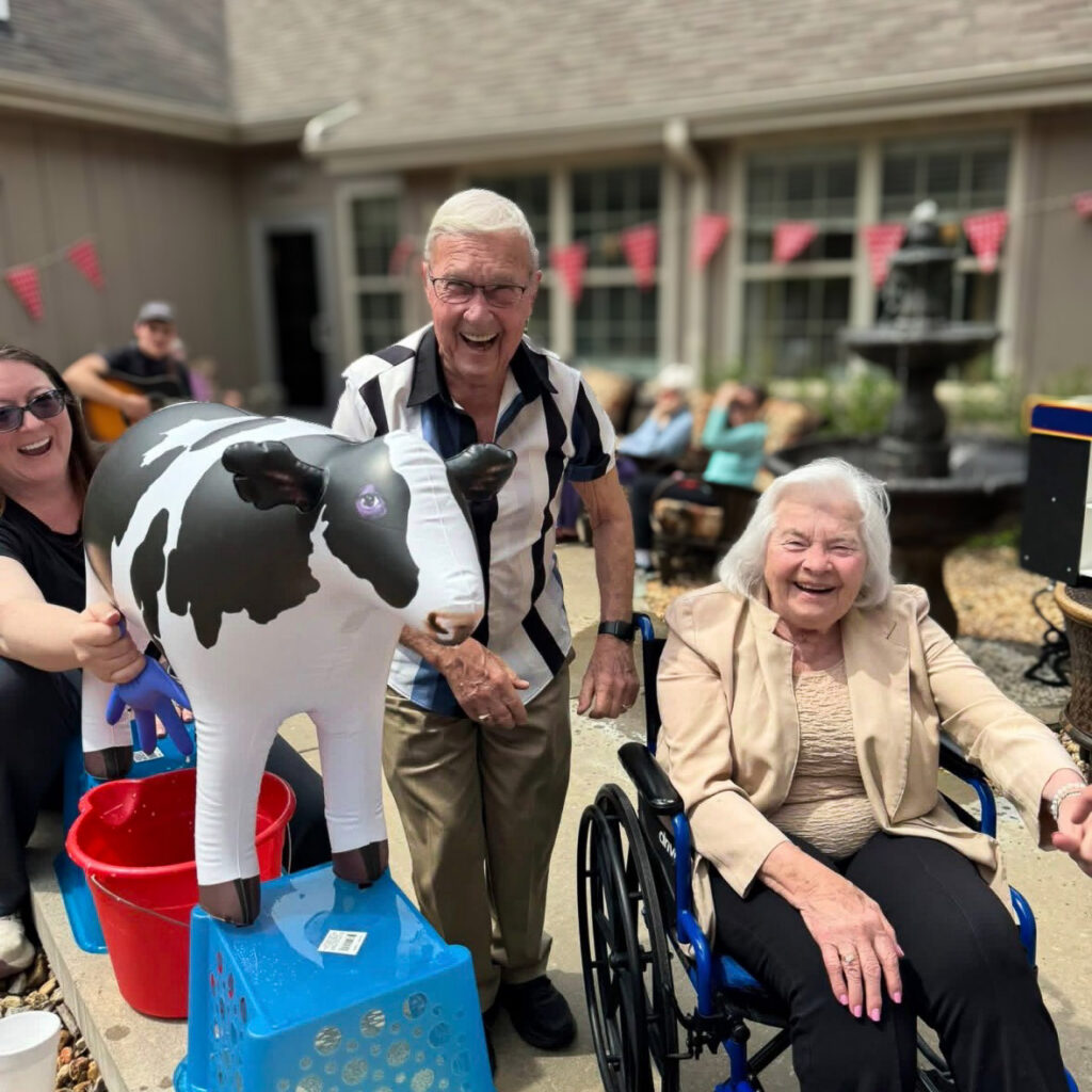 A senior man and woman smile brightly, enjoying an outdoor celebration at The Castlewood Senior Living.